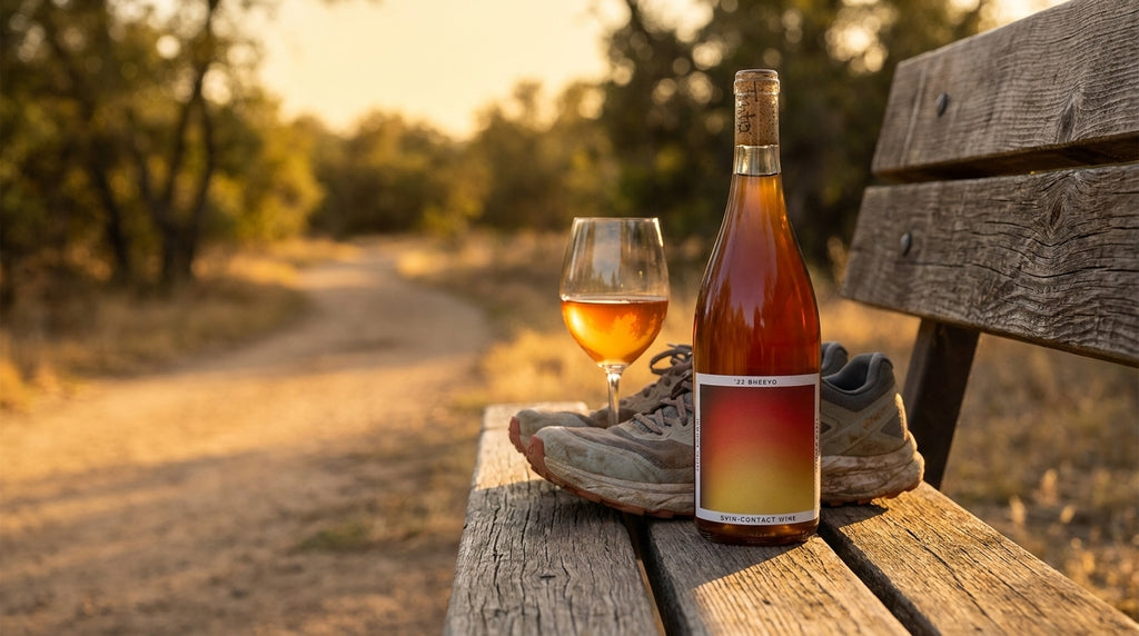 Bheeyo skin-contact orange wine bottle on a trailhead bench at golden hour after a run